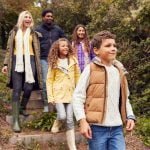 Multi-Cultural Family Walking Down Steps In Countryside On Winter Beach Vacation
