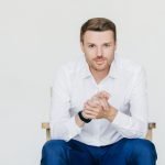 Handsome self confident businessman in white shirt and black trousers, looks with serious expression