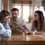 Caucasian parents arguing with teenager girl and holding mobile phone in hands