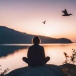 Person meditating by lake at sunset, birds flying.
