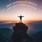 Person on mountain at sunset with outstretched arms.