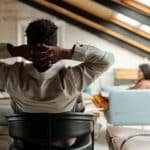 Rear view of young restful African American businessman sitting in armchair