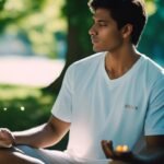 Man meditating and reading in park at sunset.