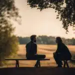 Two people chatting on park bench at dusk.