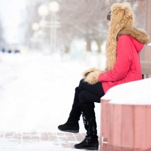 Lonely woman sitting on the bench in park in wintertime